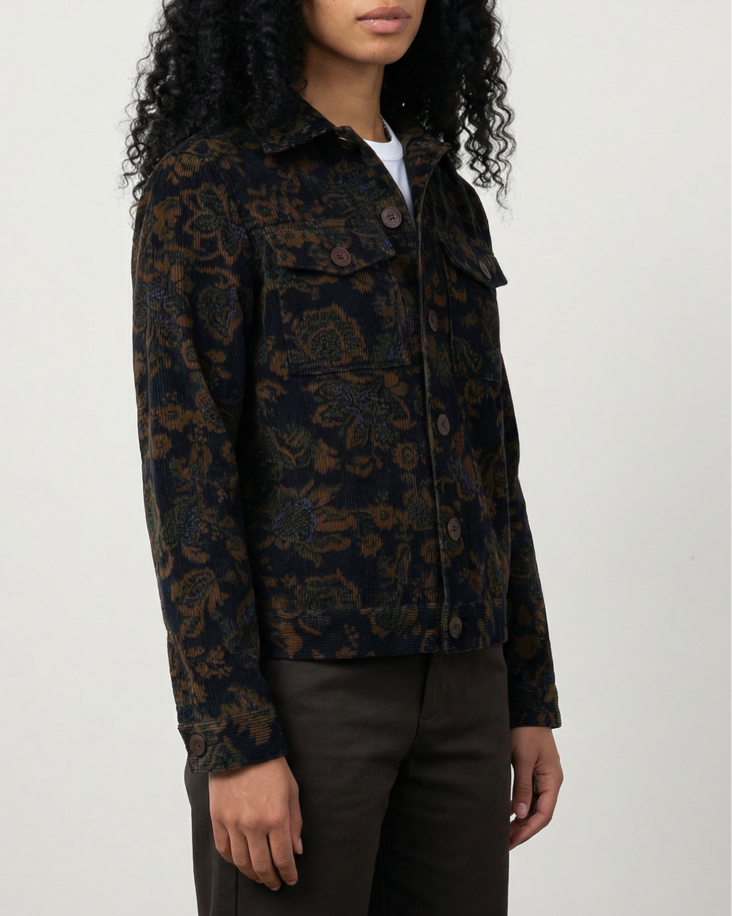 Woman wearing Dean Jacket in black and brown calico floral corduroy with relaxed boxy fit, shown from front at hip length.