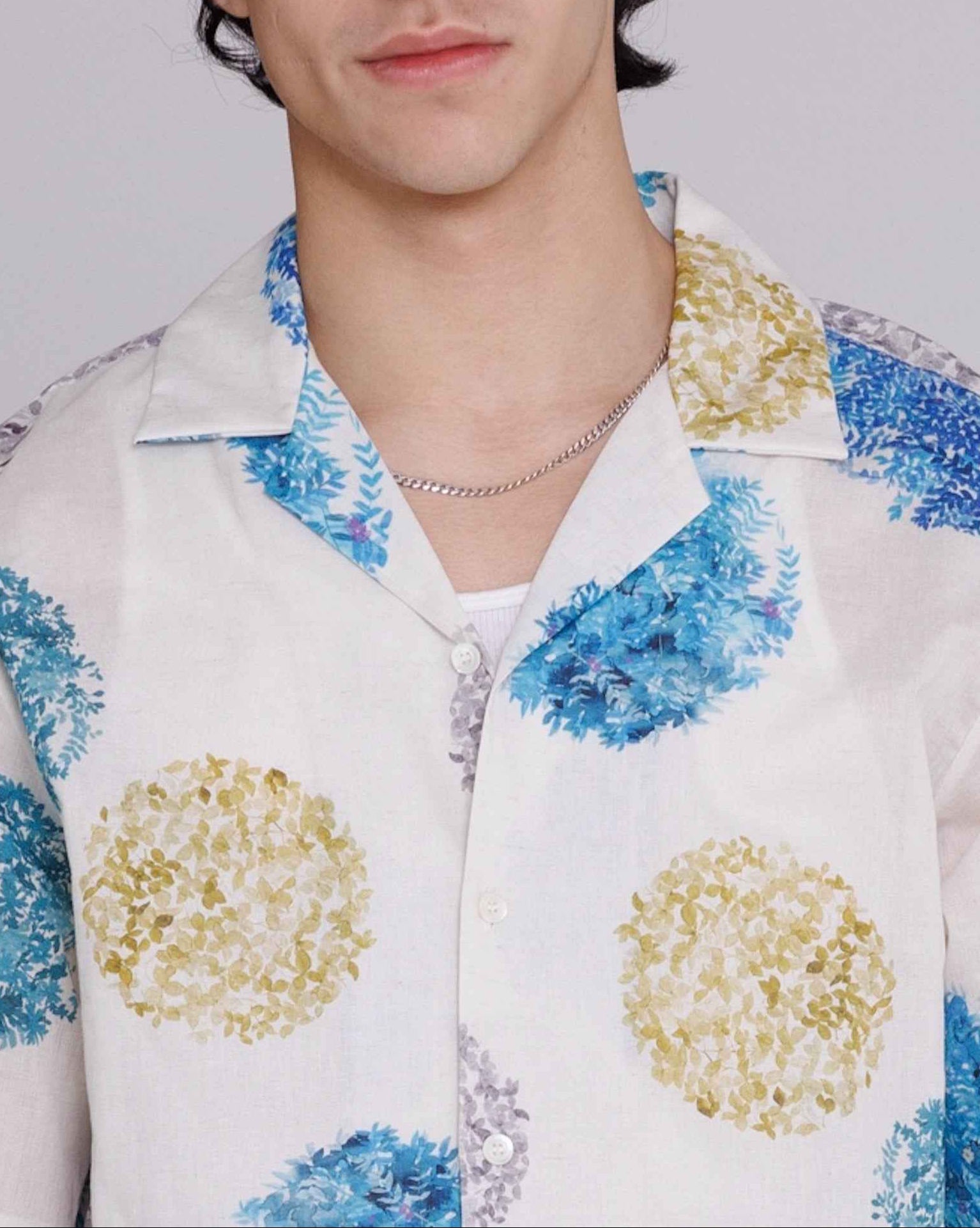 Arnaz Resort Shirt in blue and gold watercolor leaves print, cropped wider fit, worn by model in three-quarter view showing side seam openings and back pleating detail.
