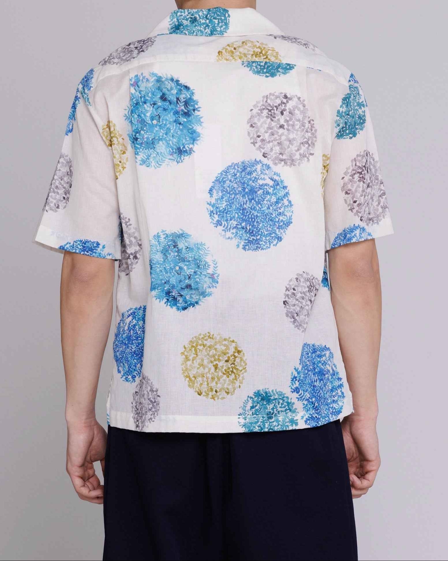 Arnaz Resort Shirt in blue and gold watercolor leaves print, cropped fit, worn by model, cotton linen fabric with side seam openings.