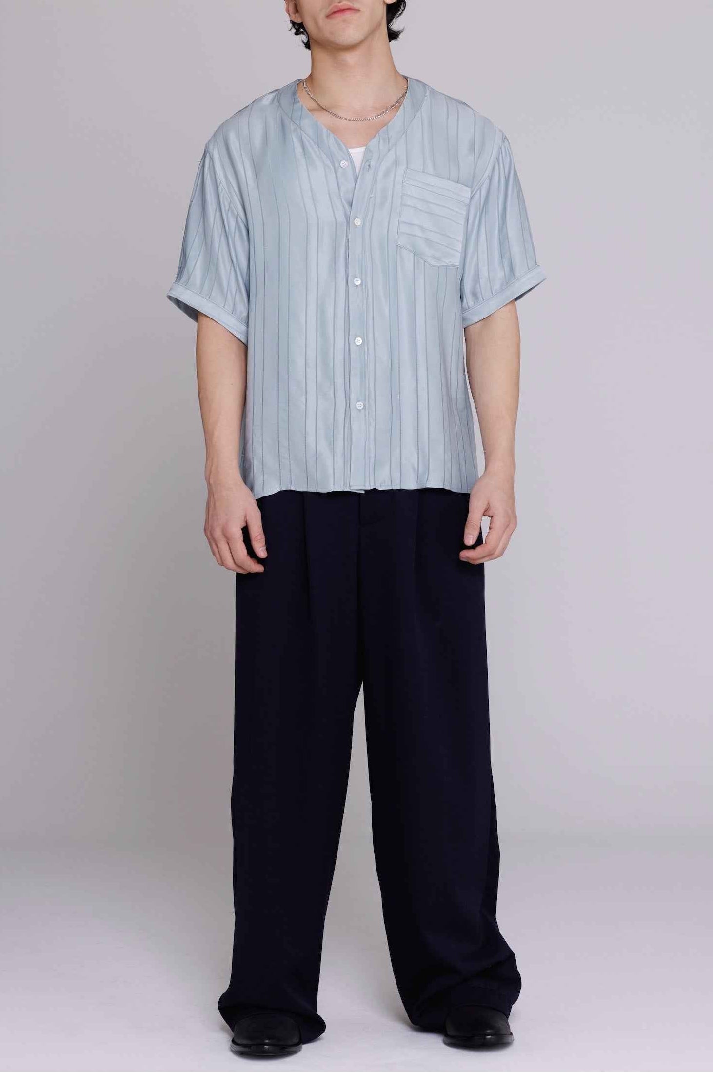 Valenzuela baseball collar shirt in blue satin stripe cupro blend, relaxed fit, shown on model from chest up against neutral background.