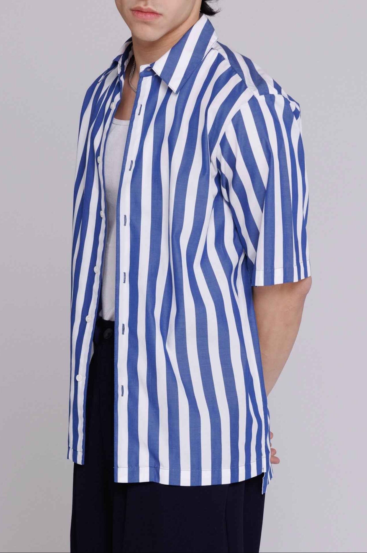 Flowers" button-up shirt in blue and white bar stripes on model, relaxed fit cotton poplin, side seam openings visible.