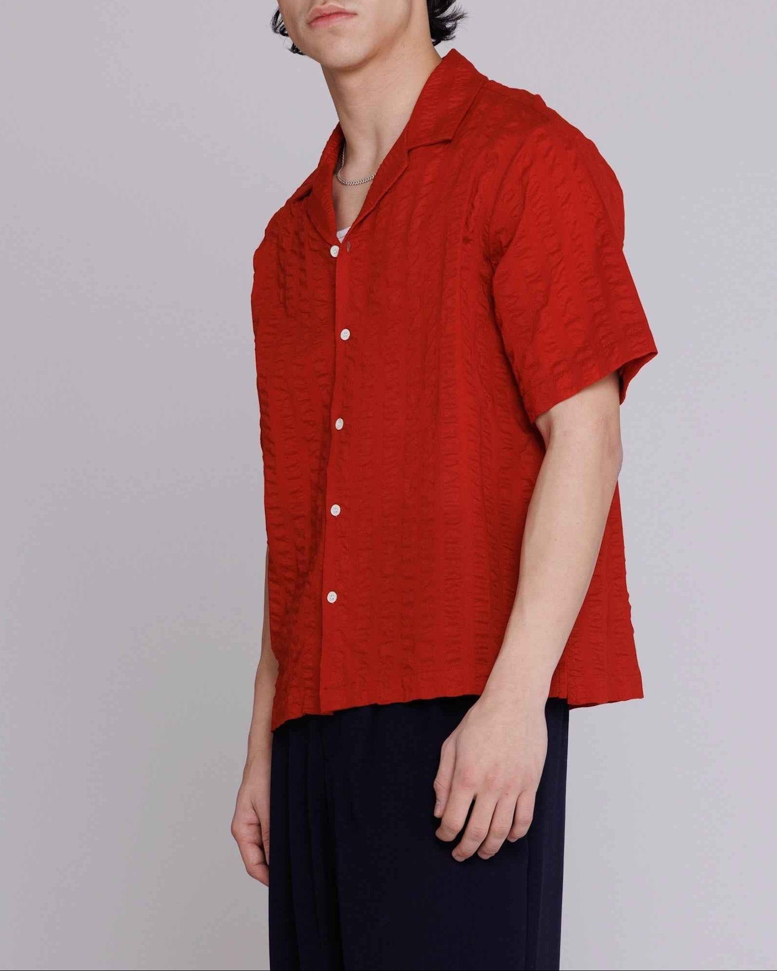 Arnaz Resort Shirt in cherry red seersucker with wide textured stripes, shown on model from chest up, displaying cropped wider fit and mother of pearl buttons.
