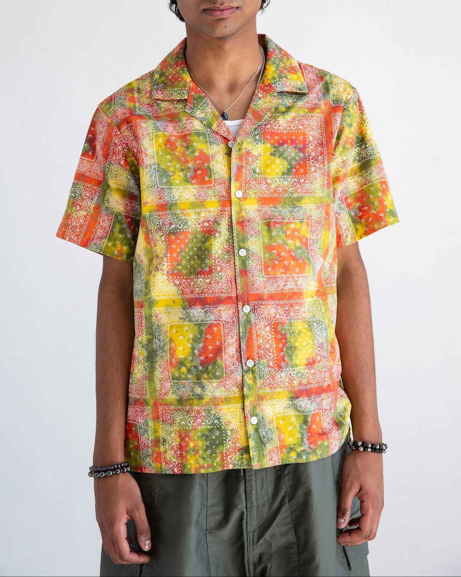 Desi short sleeve resort shirt in red batik bandana print, Cuban collar, organic cotton poplin, relaxed fit with side slits, displayed on model.