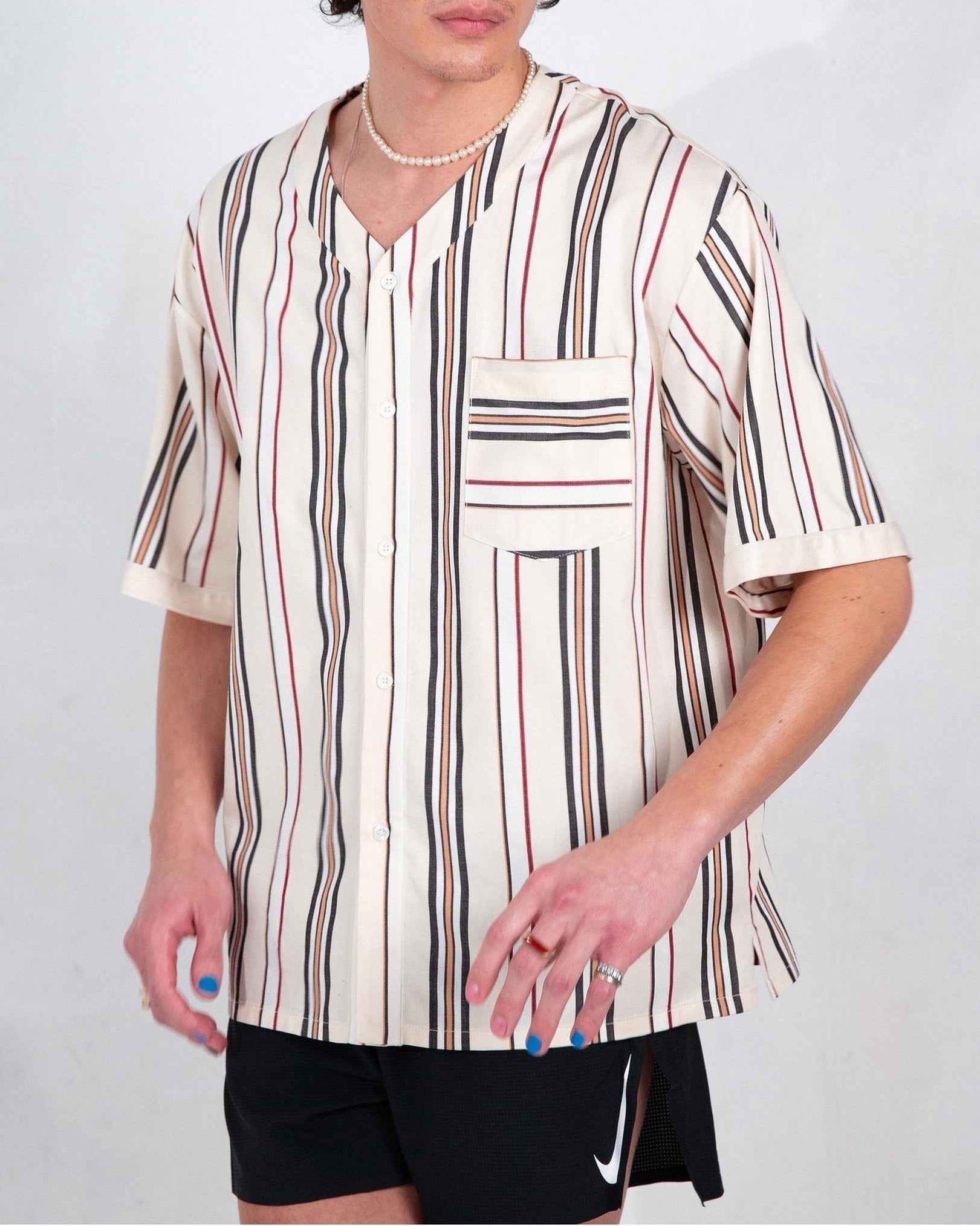 Valenzuela cream striped baseball shirt on model, relaxed boxy fit with side slits and chest pocket visible.