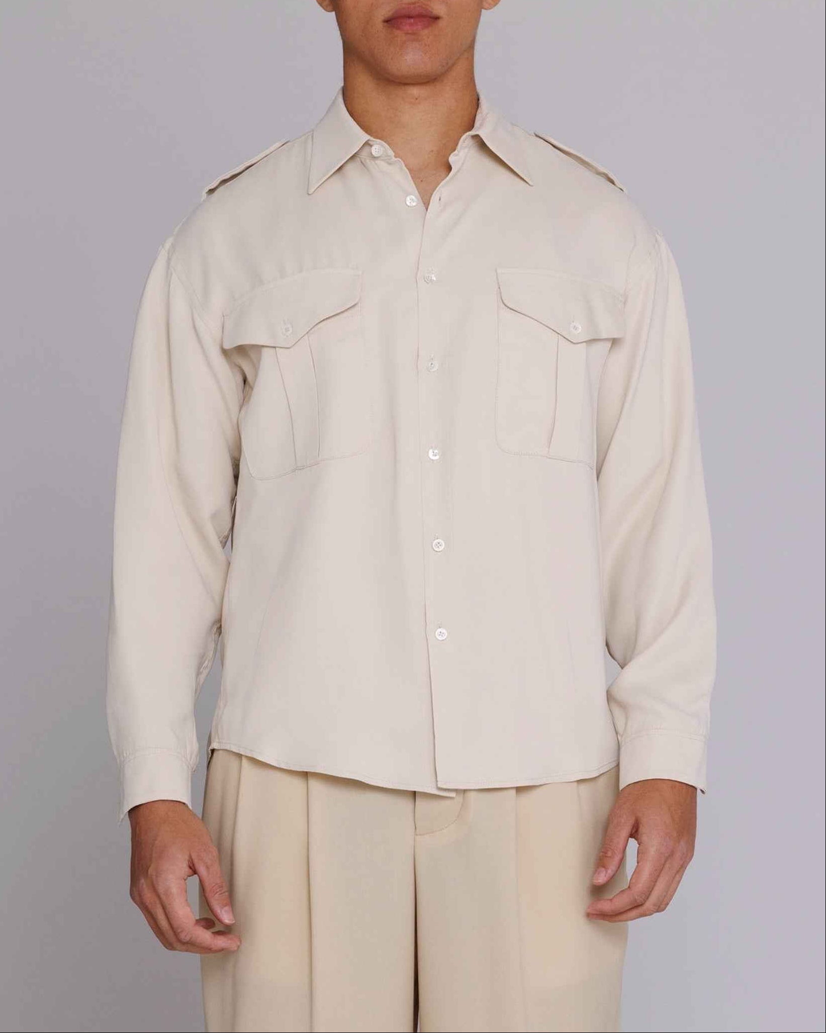 Jones" Safari Shirt in natural matte cupro satin with spread collar, chest pockets, and shoulder epaulets, modeled in medium.