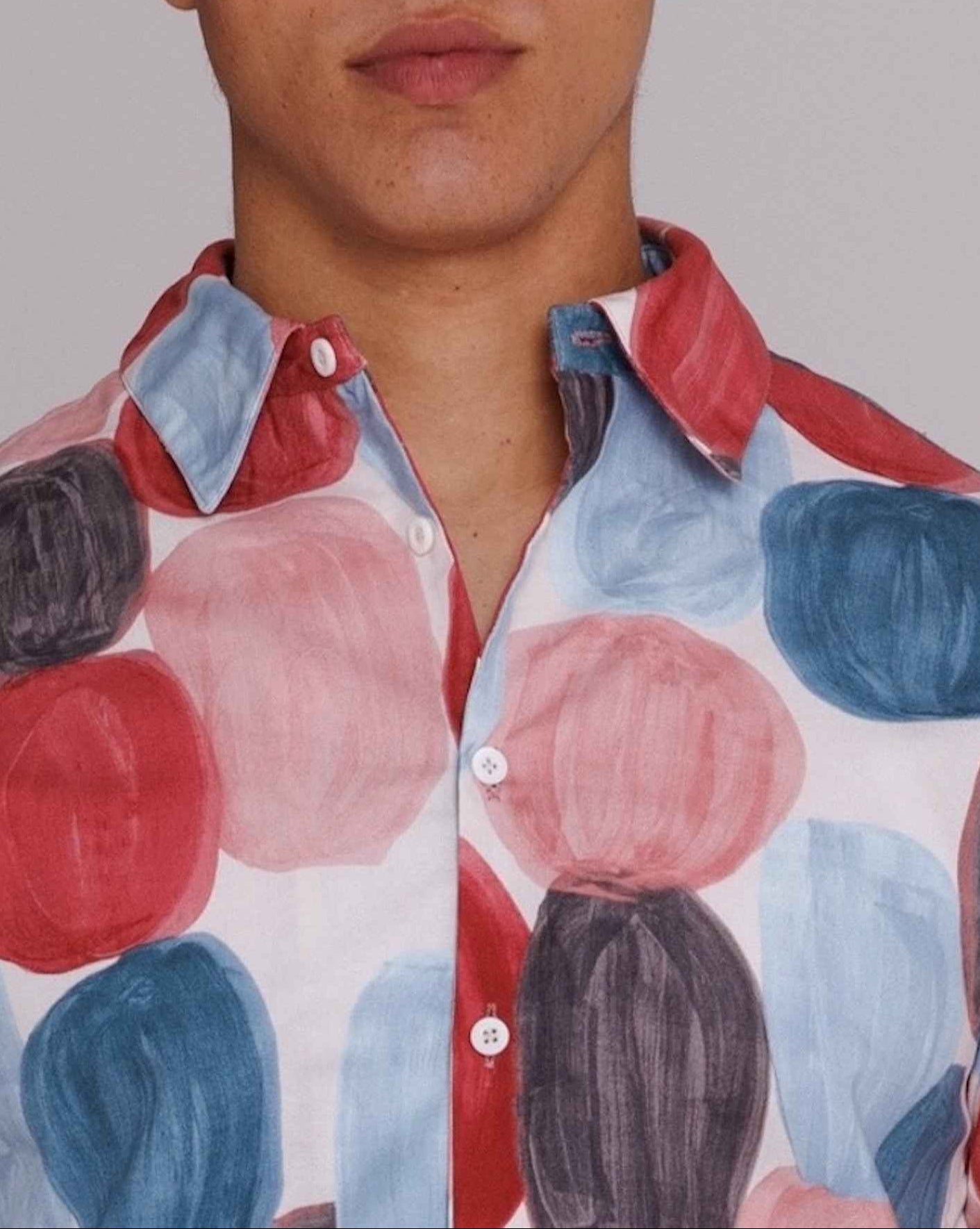 Flowers" button-up shirt in red, blue, and black dot print on model, loose fit, cotton poplin, mother of pearl buttons.