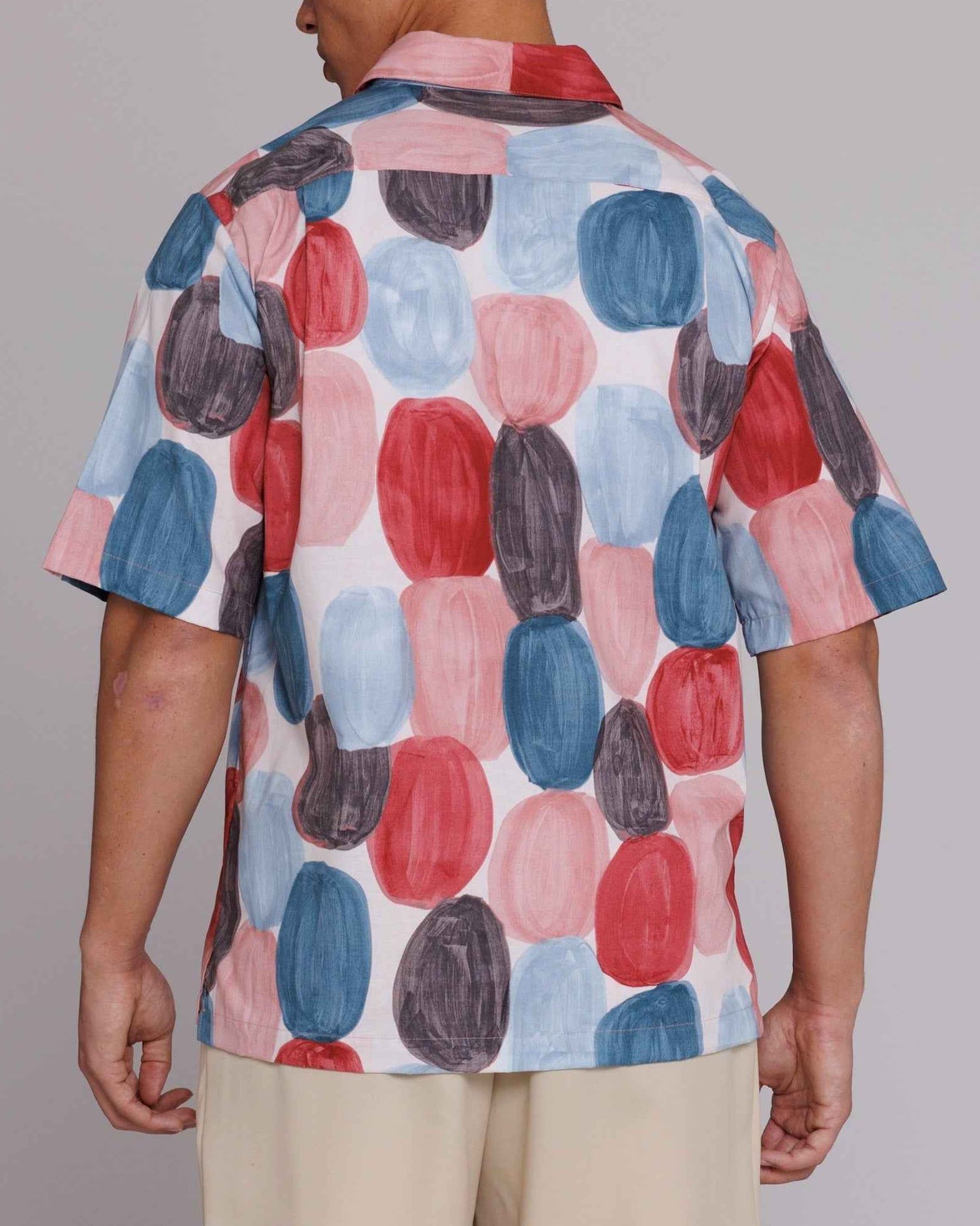 Flowers" button-up shirt in red, blue, and black dot print on model, loose fit, cotton poplin fabric with painterly brushstrokes
