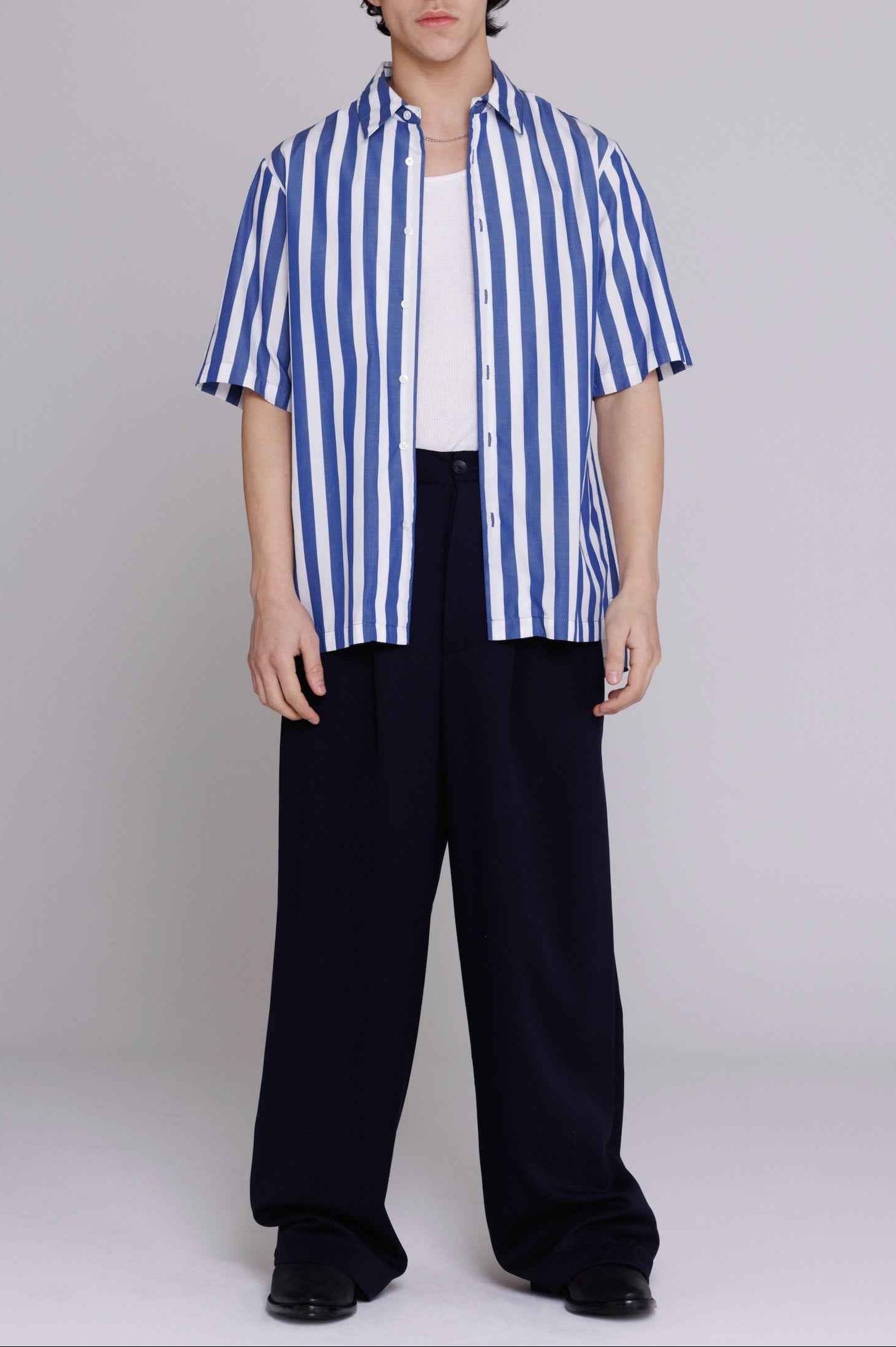 Flowers" button-up shirt in blue and white bar stripes with relaxed fit, worn by model, cotton poplin fabric with mother of pearl buttons.