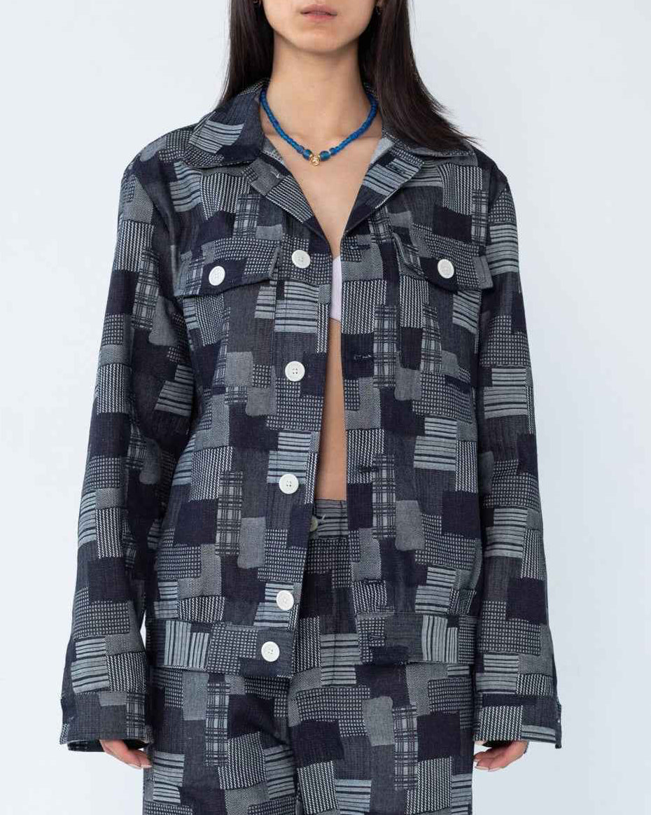 Dean Jacket in dark indigo patchwork jacquard denim with relaxed boxy fit, shown on model in three-quarter view highlighting textured fabric and dropped shoulder construction.