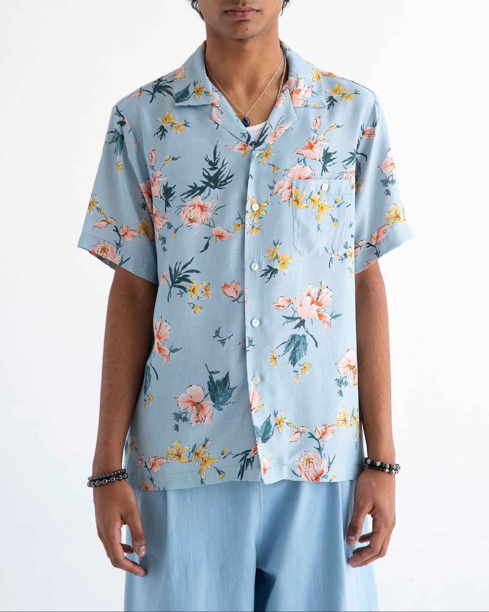 Desi short sleeve camp collar shirt in light blue Ukiyoe hibiscus print, displayed on model showing rayon poplin fabric and side slits.