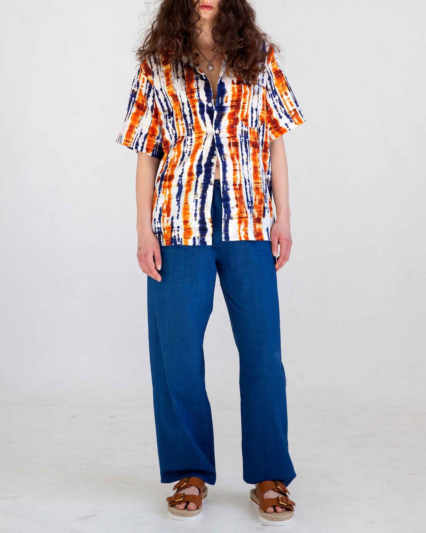 Desi short sleeve resort shirt in blue and orange batik print with Cuban collar, displayed on model in relaxed fit camp style.
