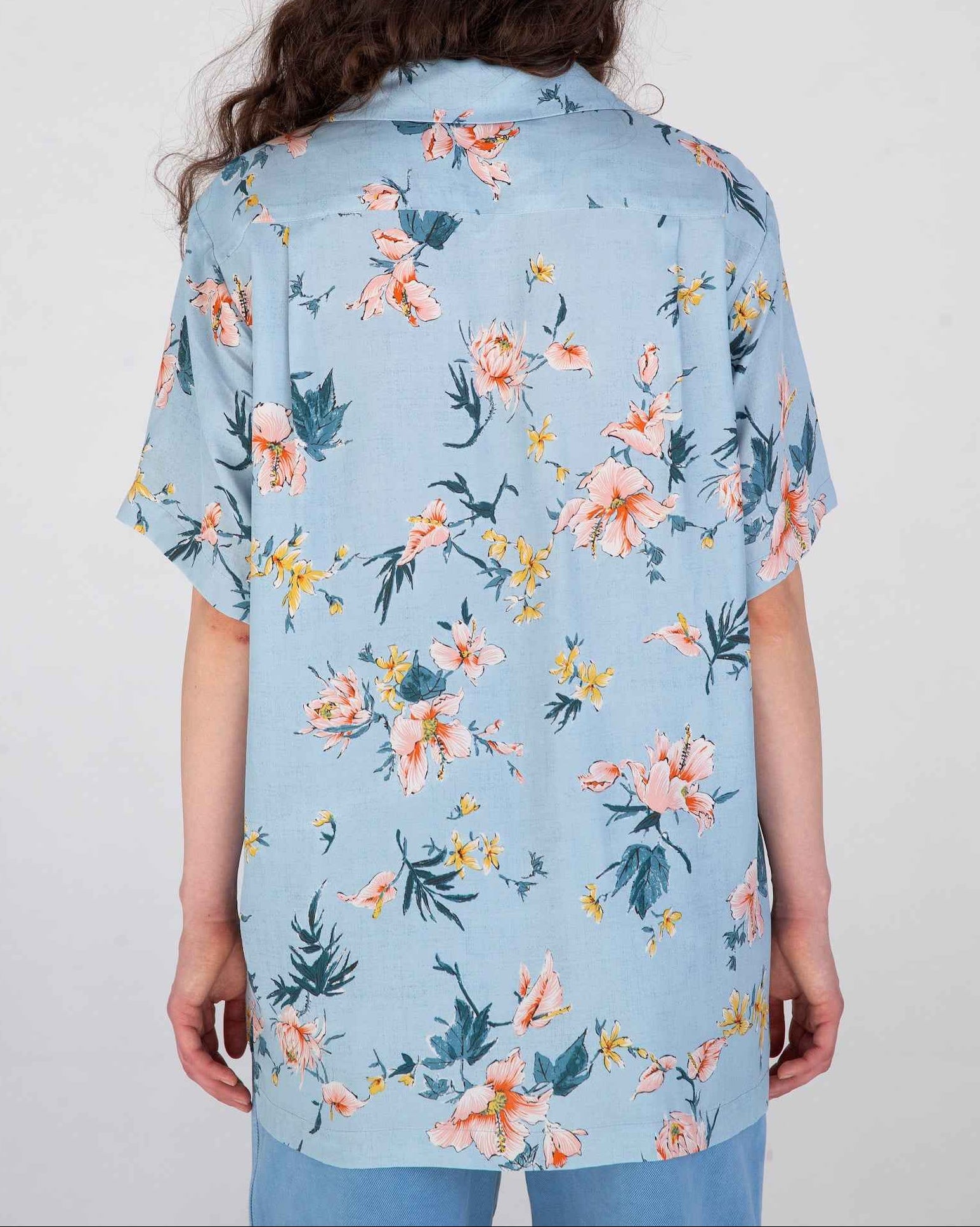 Desi short sleeve resort shirt in light blue Ukiyoe hibiscus print, rayon poplin fabric, camp collar, displayed on model.