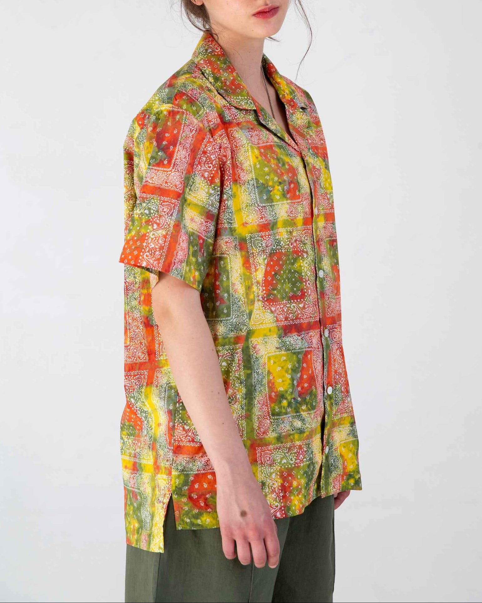 Desi red batik bandana print short sleeve resort shirt with Cuban collar, displayed on model showing relaxed fit and side slits.