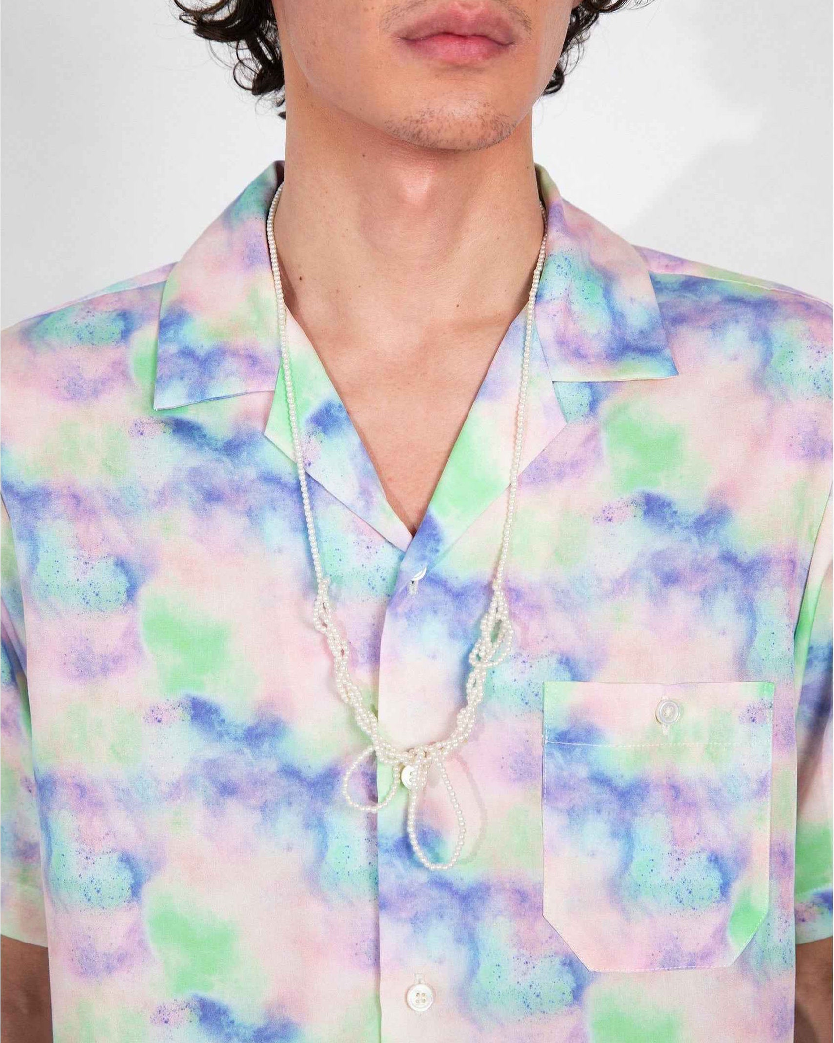 Desi Camp Collar shirt in Blue Dream Pop Print worn untucked, relaxed resort fit, short sleeves, vibrant blue artistic print on lightweight cotton fabric.