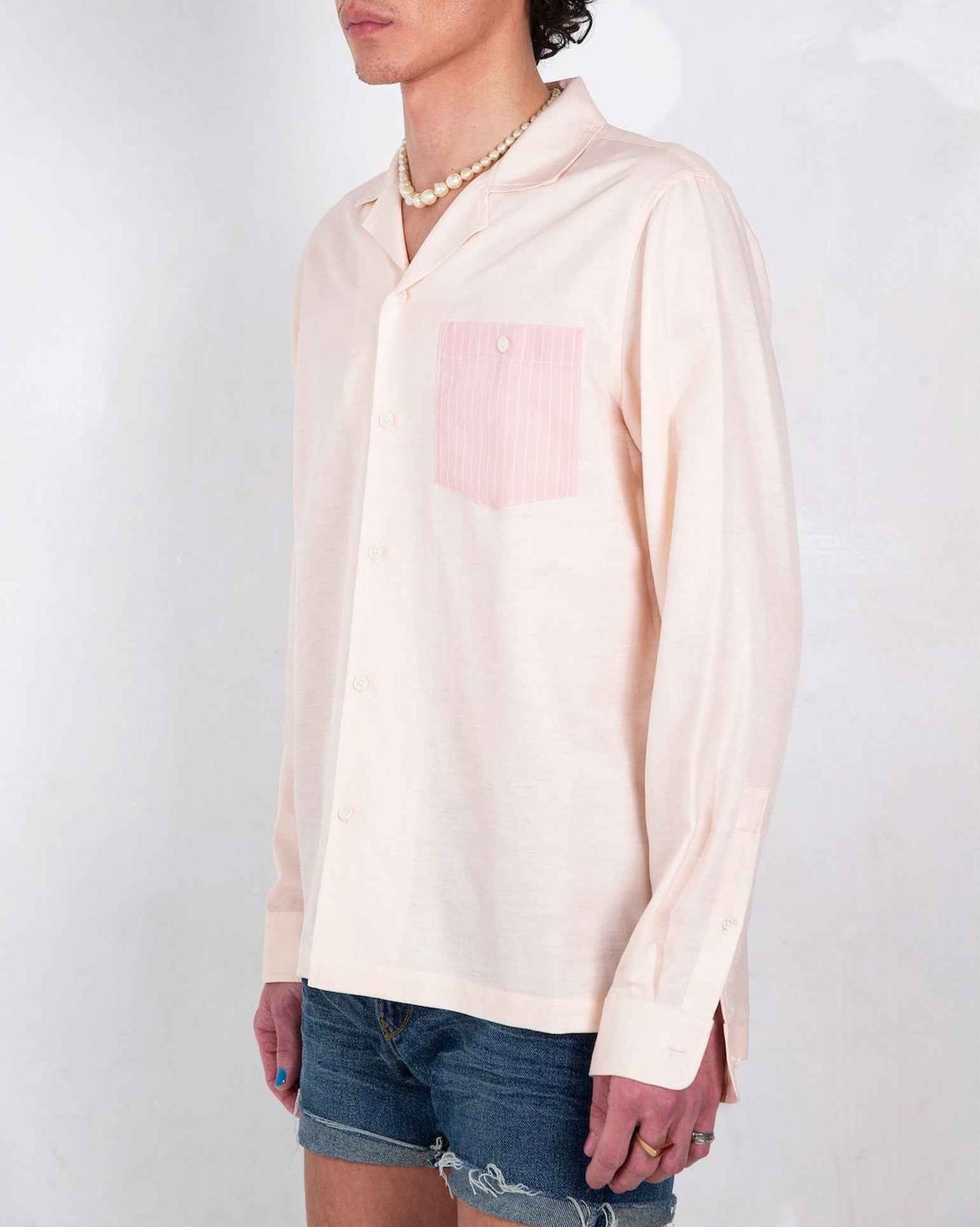 Arenas convertible-collar shirt in blush and white stripe cotton linen cupro twill, relaxed fit, worn untucked with striped pocket detail visible.