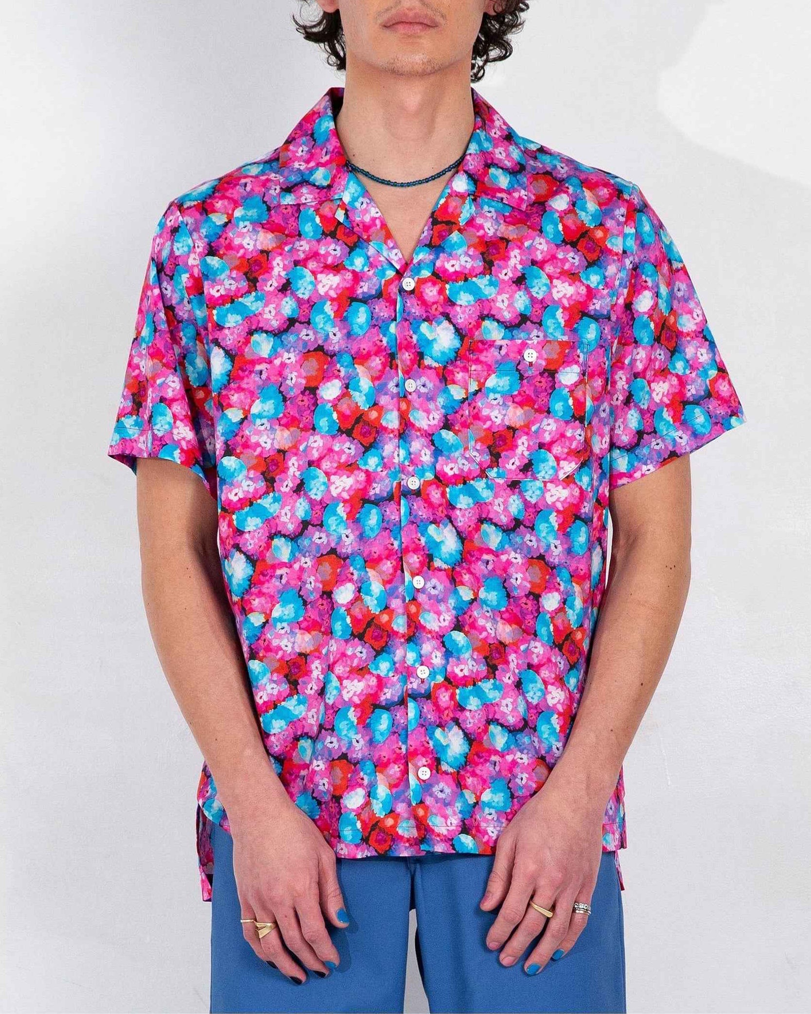 Desi camp collar shirt in red floral dream print, soft cotton and Tencel twill, relaxed fit with side slits, worn by model in front-facing pose.