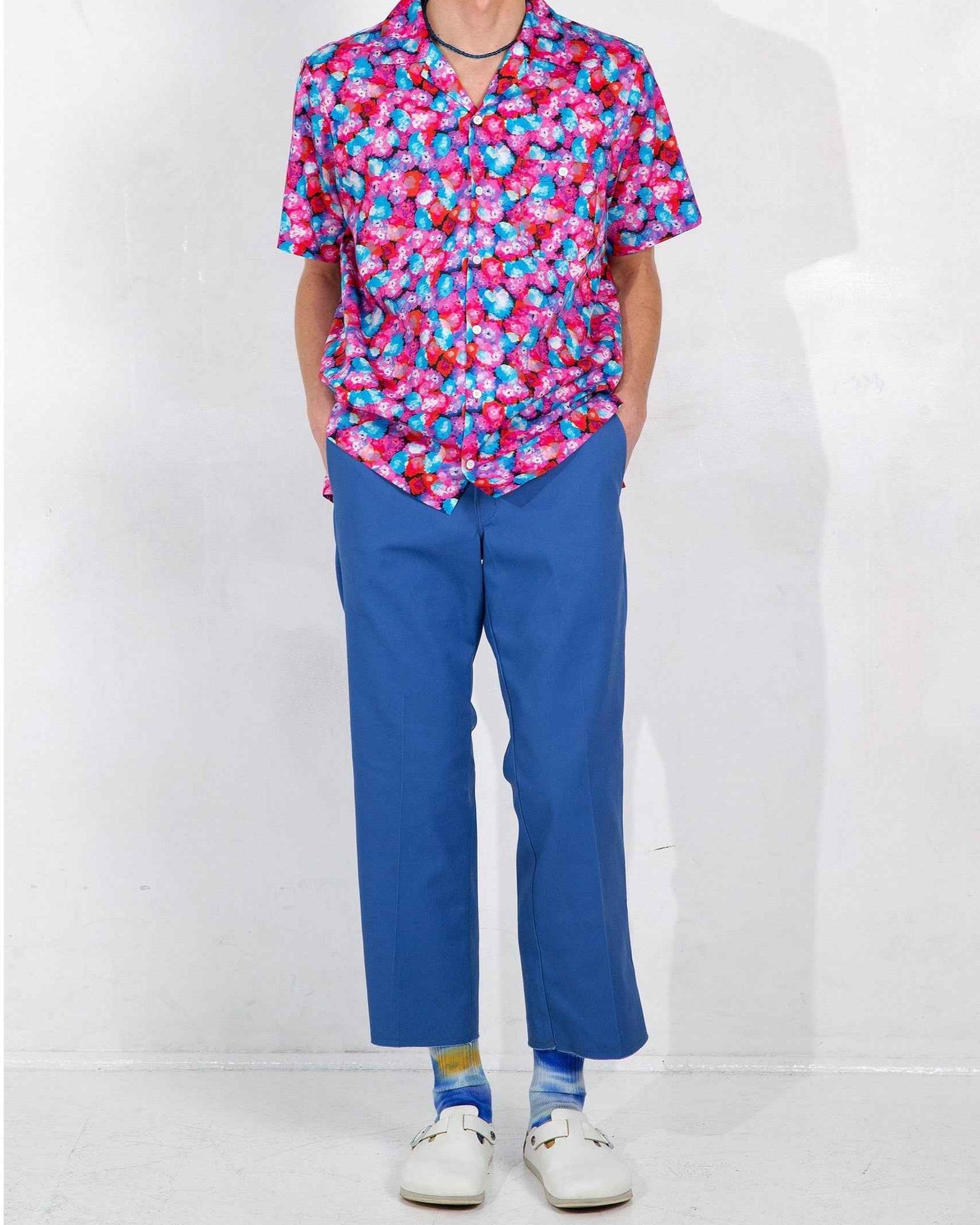 Desi camp collar shirt in red floral dream print, relaxed fit with side slits, modeled on standing figure
