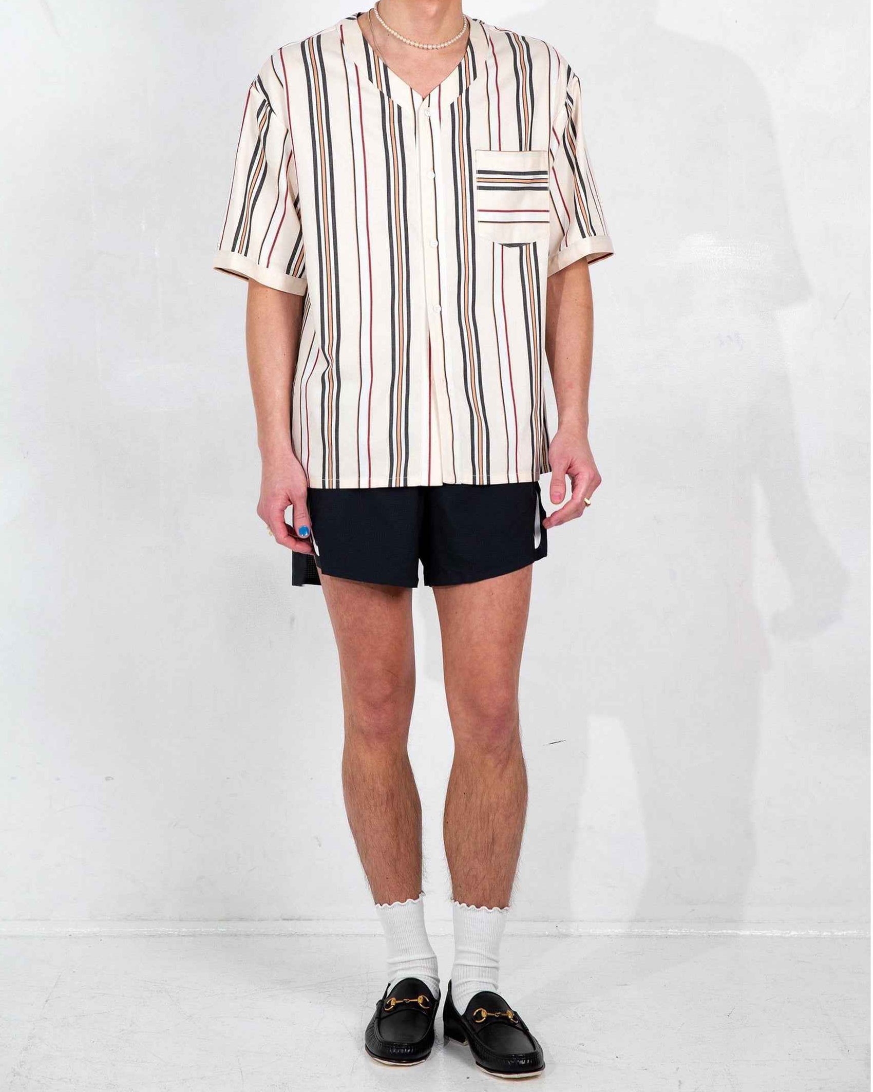 Cream and white striped baseball collar shirt on model, relaxed boxy fit with side slits, short sleeves, front chest pocket visible.